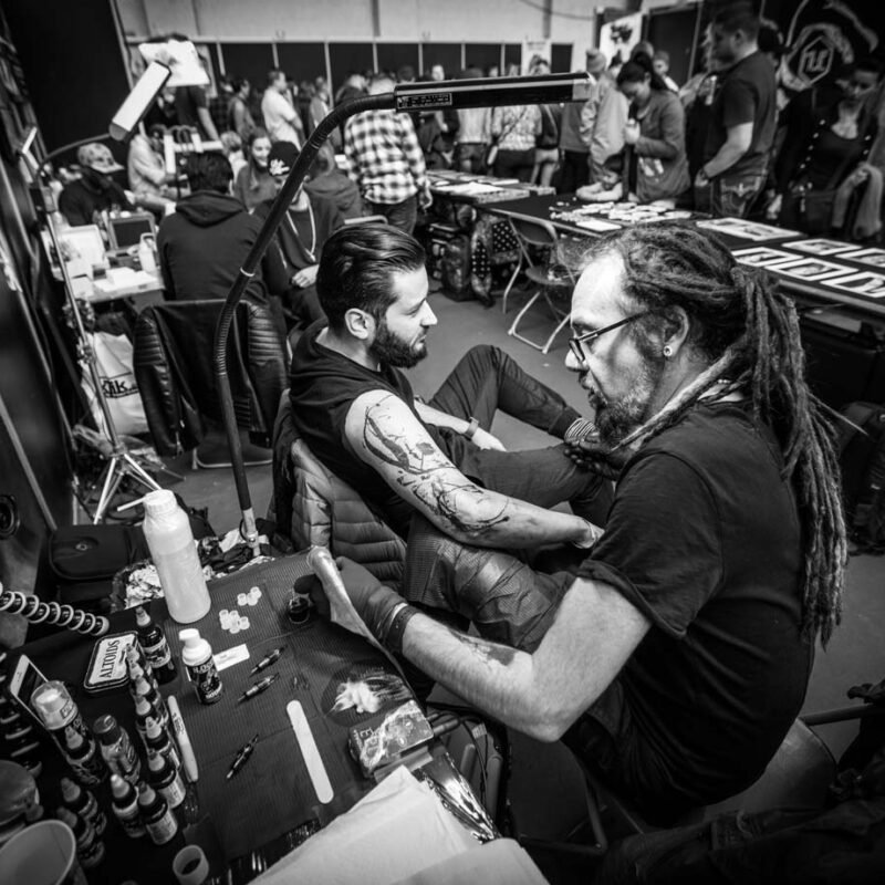 Tattoo artist working on a custom tattoo during a tattoo convention